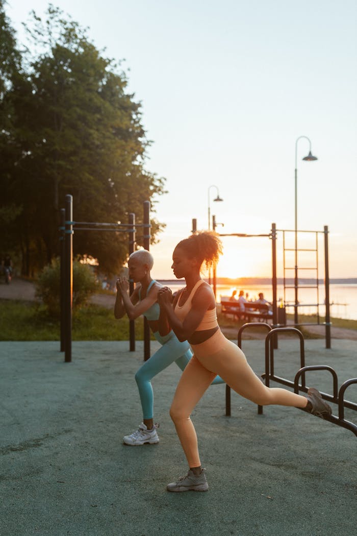 Two women exercising outdoors at sunset, demonstrating fitness and health.